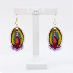 04_ARETE BADGE VIRGENCITA 2025 SAO Virgin of Guadalupe earrings hanging on a cat-shaped display stand